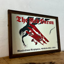 Load image into Gallery viewer, Vintage Red Baron plane mirror featuring vivid picture of the plane in bright colours with a battle scene over the mirror and bold font describing the pilot name and the dates, more historical detail about the piece further down.