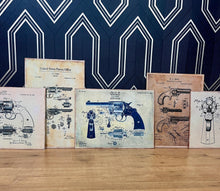 Load image into Gallery viewer, This collection features seven stunning vintage-style artworks of guns, revolvers, and shotguns. These prints, likely created in the 1990s, are displayed on old wooden sheets.