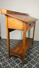 Load image into Gallery viewer, Excellent pitch pine clerk desk with raised back and sloped writing surface over a single fall-front cupboard with key, raised on square supports united by under-tier two plank pine shelf.