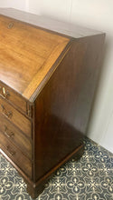Load image into Gallery viewer, The antique mahogany bureau has a fall front that opens to reveal a writing surface. Its elegant fitted interior consists of six pigeon holes, five drawers on either side, and a central cupboard with Roman columns with a gold detail sitting on desirable runners