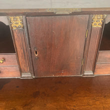 Load image into Gallery viewer, The antique mahogany bureau has a fall front that opens to reveal a writing surface. Its elegant fitted interior consists of six pigeon holes, five drawers on either side, and a central cupboard with Roman columns with a gold detail sitting on desirable runners
