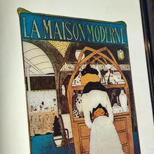 Load image into Gallery viewer, It was designed by Maurice Biais, a notable artist and designer of the Belle Époque style. The poster showcases a woman admiring the Art Nouveau items available at the gallery.