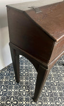 Load image into Gallery viewer, Constructed from rich dark oak, it features a plain, authentic craftsmanship design supported by chunky tapered legs. The hinged lid features excellent dark iron pads with a striking bolt finish. The interior includes a drawer panel that opens to reveal two hidden drawers that slide across, adding a touch of period charm