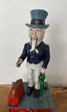 Load image into Gallery viewer, This mechanical coin bank features Uncle Sam, the national personification of the U.S. government. It is made of cast iron and hand-painted. When a coin is placed in Uncle Sam's hand and a lever is pressed, his arm moves down, depositing the coin into a bag and then into the bank's base; his beard also moves.