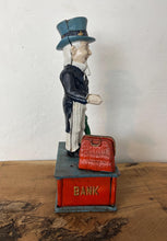 Load image into Gallery viewer, This mechanical coin bank features Uncle Sam, the national personification of the U.S. government. It is made of cast iron and hand-painted. When a coin is placed in Uncle Sam's hand and a lever is pressed, his arm moves down, depositing the coin into a bag and then into the bank's base; his beard also moves.