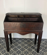 Load image into Gallery viewer, Constructed from rich dark oak, it features a plain, authentic craftsmanship design supported by chunky tapered legs. The hinged lid features excellent dark iron pads with a striking bolt finish. The interior includes a drawer panel that opens to reveal two hidden drawers that slide across, adding a touch of period charm