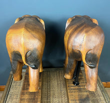 Load image into Gallery viewer, The elephants are carved from rosewood, with a two-tone finish that highlights the details of the skin and body. The carvings are detailed, showing the texture of the skin, the shape of the ears, and the tusks.