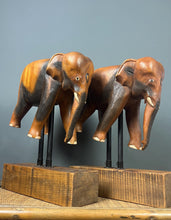 Load image into Gallery viewer, The elephants are carved from rosewood, with a two-tone finish that highlights the details of the skin and body. The carvings are detailed, showing the texture of the skin, the shape of the ears, and the tusks.