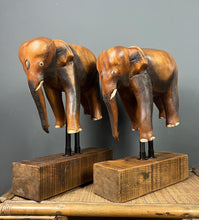 Load image into Gallery viewer, The elephants are carved from rosewood, with a two-tone finish that highlights the details of the skin and body. The carvings are detailed, showing the texture of the skin, the shape of the ears, and the tusks.
