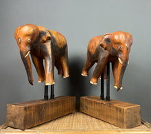 Load image into Gallery viewer, The elephants are carved from rosewood, with a two-tone finish that highlights the details of the skin and body. The carvings are detailed, showing the texture of the skin, the shape of the ears, and the tusks.