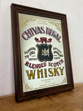 Load image into Gallery viewer, The mirror features vibrant, bold fonts in fabulous colours, with the royal crest in the middle and an intricate golden border. It is presented in a wooden frame and is in vintage condition, with a few signs of authentic patina.