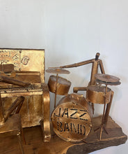 Load image into Gallery viewer, It features abstract, elongated figures of musicians playing various instruments, including a guitar, double bass, trumpet, trombone, saxophone, piano, and drums.