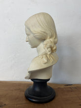 Load image into Gallery viewer, The figure depicts a young woman with wavy hair gathered into ringlets over her shoulders, wearing a draped garment with spaghetti straps and rosette detailing. Her facial expression is serene with downcast eyes.