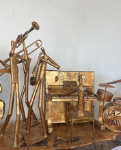 Load image into Gallery viewer, It features abstract, elongated figures of musicians playing various instruments, including a guitar, double bass, trumpet, trombone, saxophone, piano, and drums.