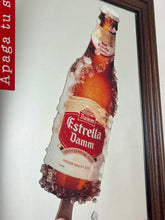 Load image into Gallery viewer, The main image is a unique graphic of an ice-encrusted Estrella Damm bottle held like a popsicle or ice lolly by a hand.