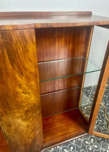 Load image into Gallery viewer, This beautiful piece is a 1930s English Art Deco cocktail cabinet, characterized by its figured walnut veneers and distinctive geometric glazed doors.