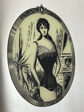 Load image into Gallery viewer, The mirror depicts a glamorous Victorian lady in an oval design with a noir effect, and it includes intricate details and a provocative finish. The walnut frame is of high quality and dates back to the 1920s.