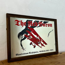 Load image into Gallery viewer, Vintage Red Baron plane mirror featuring vivid picture of the plane in bright colours with a battle scene over the mirror and bold font describing the pilot name and the dates, more historical detail about the piece further down.