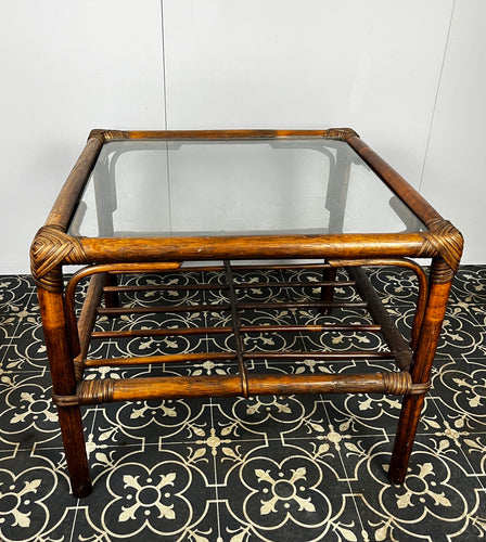 Stunning intertwined woven corners with magnificent craftsmanship finish towards the bottom of a bamboo rack to store books or newspapers come with a sleek glass top.