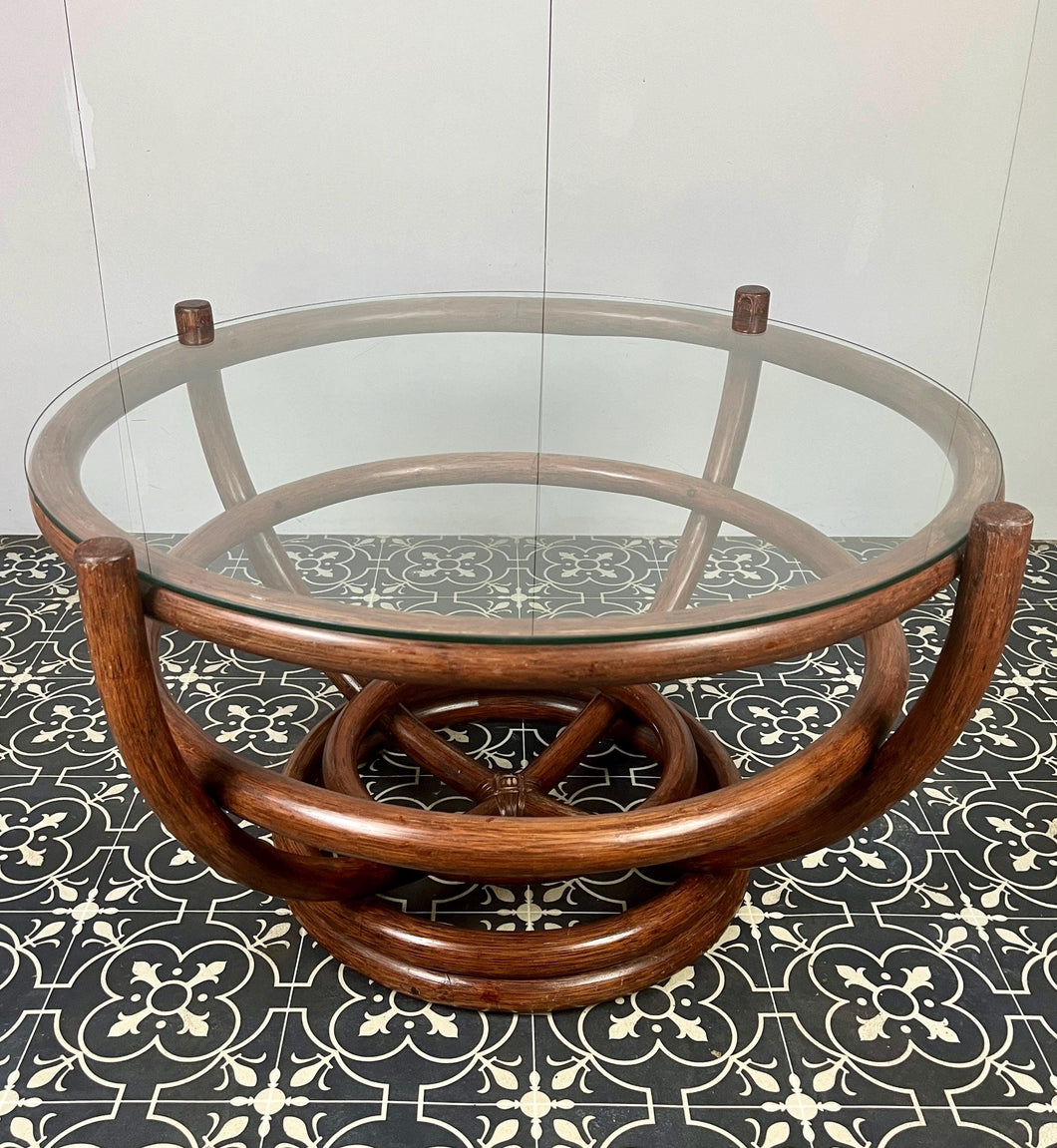 Stunning intertwined bentwood frame with magnificent craftsmanship finish towards the bottom of a woven bamboo base with a sleek glass top.