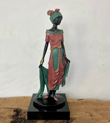 This beautiful art deco figure features an elegant lady posing wearing a stylish green and pink dress, hat, and bow with a nice sparkling effect. We particularly liked the flowing shoal in the piece.