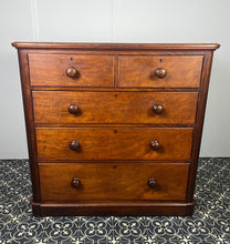 Load image into Gallery viewer, Good quality large antique Victorian mahogany chest of drawers with curved corners, turned bun handles, and a part missing underneath one handle. The bottom drawer is deep and has the plinth attached.
