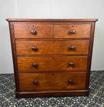 Load image into Gallery viewer, Good quality large antique Victorian mahogany chest of drawers with curved corners, turned bun handles, and a part missing underneath one handle. The bottom drawer is deep and has the plinth attached.
