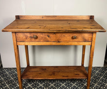 Load image into Gallery viewer, Excellent pitch pine clerk desk with raised back and sloped writing surface over a single fall-front cupboard with key, raised on square supports united by under-tier two plank pine shelf.
