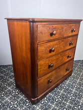 Load image into Gallery viewer, Good quality large antique Victorian mahogany chest of drawers with curved corners, turned bun handles, and a part missing underneath one handle. The bottom drawer is deep and has the plinth attached.
