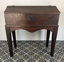 Load image into Gallery viewer, Constructed from rich dark oak, it features a plain, authentic craftsmanship design supported by chunky tapered legs. The hinged lid features excellent dark iron pads with a striking bolt finish. The interior includes a drawer panel that opens to reveal two hidden drawers that slide across, adding a touch of period charm
