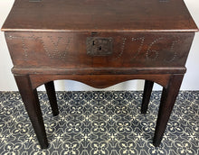 Load image into Gallery viewer, Constructed from rich dark oak, it features a plain, authentic craftsmanship design supported by chunky tapered legs. The hinged lid features excellent dark iron pads with a striking bolt finish. The interior includes a drawer panel that opens to reveal two hidden drawers that slide across, adding a touch of period charm
