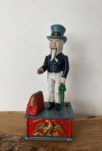 Load image into Gallery viewer, This mechanical coin bank features Uncle Sam, the national personification of the U.S. government. It is made of cast iron and hand-painted. When a coin is placed in Uncle Sam&#39;s hand and a lever is pressed, his arm moves down, depositing the coin into a bag and then into the bank&#39;s base; his beard also moves.
