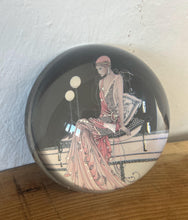 Load image into Gallery viewer, Beautiful vintage glass paperweight in Art Deco style, featuring an illustration of a lady in a pink dress and headpiece. This particular style, often associated with the roaring twenties, is characterised by its elegant and sophisticated portrayal of women, usually referred to as flapper ladies or Gatsby ladies.

