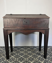Load image into Gallery viewer, Constructed from rich dark oak, it features a plain, authentic craftsmanship design supported by chunky tapered legs. The hinged lid features excellent dark iron pads with a striking bolt finish. The interior includes a drawer panel that opens to reveal two hidden drawers that slide across, adding a touch of period charm
