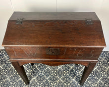 Load image into Gallery viewer, Constructed from rich dark oak, it features a plain, authentic craftsmanship design supported by chunky tapered legs. The hinged lid features excellent dark iron pads with a striking bolt finish. The interior includes a drawer panel that opens to reveal two hidden drawers that slide across, adding a touch of period charm
