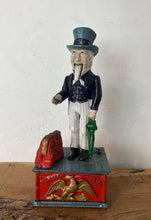 Load image into Gallery viewer, This mechanical coin bank features Uncle Sam, the national personification of the U.S. government. It is made of cast iron and hand-painted. When a coin is placed in Uncle Sam&#39;s hand and a lever is pressed, his arm moves down, depositing the coin into a bag and then into the bank&#39;s base; his beard also moves.
