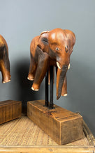 Load image into Gallery viewer, The elephants are carved from rosewood, with a two-tone finish that highlights the details of the skin and body. The carvings are detailed, showing the texture of the skin, the shape of the ears, and the tusks.
