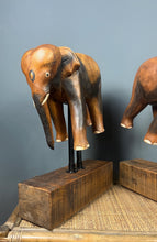 Load image into Gallery viewer, The elephants are carved from rosewood, with a two-tone finish that highlights the details of the skin and body. The carvings are detailed, showing the texture of the skin, the shape of the ears, and the tusks.
