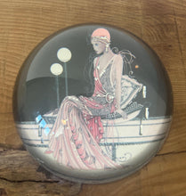 Load image into Gallery viewer, Beautiful vintage glass paperweight in Art Deco style, featuring an illustration of a lady in a pink dress and headpiece. This particular style, often associated with the roaring twenties, is characterised by its elegant and sophisticated portrayal of women, usually referred to as flapper ladies or Gatsby ladies.
