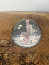 Load image into Gallery viewer, Beautiful vintage glass paperweight in Art Deco style, featuring an illustration of a lady in a pink dress and headpiece. This particular style, often associated with the roaring twenties, is characterised by its elegant and sophisticated portrayal of women, usually referred to as flapper ladies or Gatsby ladies.
