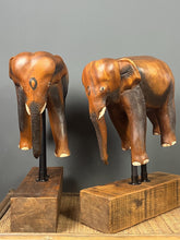 Load image into Gallery viewer, The elephants are carved from rosewood, with a two-tone finish that highlights the details of the skin and body. The carvings are detailed, showing the texture of the skin, the shape of the ears, and the tusks.
