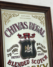 Load image into Gallery viewer, The mirror features vibrant, bold fonts in fabulous colours, with the royal crest in the middle and an intricate golden border. It is presented in a wooden frame and is in vintage condition, with a few signs of authentic patina.
