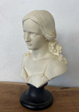 Load image into Gallery viewer, The figure depicts a young woman with wavy hair gathered into ringlets over her shoulders, wearing a draped garment with spaghetti straps and rosette detailing. Her facial expression is serene with downcast eyes.
