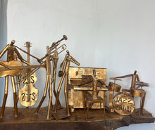 Load image into Gallery viewer, It features abstract, elongated figures of musicians playing various instruments, including a guitar, double bass, trumpet, trombone, saxophone, piano, and drums.
