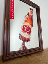 Load image into Gallery viewer, The main image is a unique graphic of an ice-encrusted Estrella Damm bottle held like a popsicle or ice lolly by a hand.
