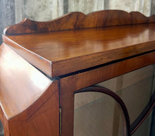 Load image into Gallery viewer, This stunning piece is an antique Art Deco display cabinet, dating from the 1930s. It is characterised by its walnut or mahogany construction, featuring astragal-glazed doors with a distinctive curved pattern and claw-and-ball feet.
