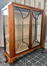 Load image into Gallery viewer, This stunning piece is an antique Art Deco display cabinet, dating from the 1930s. It is characterised by its walnut or mahogany construction, featuring astragal-glazed doors with a distinctive curved pattern and claw-and-ball feet.

