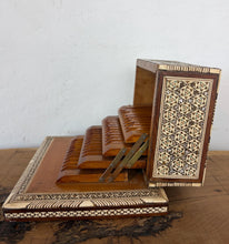 Load image into Gallery viewer, This stunning Vintage Middle Eastern Marquetry Cigarette Box features incredibly detailed, handcrafted geometric star patterns and micro-mosaic detailing. Combining traditional Khatam kari technique with natural wood, bone, and iridescent mother-of-pearl inlays, it rests on a prominent tiered pedestal base. High-quality boxes like this from the mid-20th century often feature hidden compartments or internal mechanical music boxes. It makes a sophisticated addition to any tobacciana collection.
