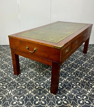 Load image into Gallery viewer, Introducing a unique piece of craftsmanship - a mahogany coffee table in the military campaign style. This stunning table, made in England around the 1950s, features a design that will pique your interest with its formal and executive look.
