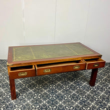 Load image into Gallery viewer, Introducing a unique piece of craftsmanship - a mahogany coffee table in the military campaign style. This stunning table, made in England around the 1950s, features a design that will pique your interest with its formal and executive look.
